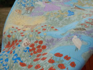 Illustrated blue silk foulard featuring the Vjosa River, red wildflowers, birds, and Albanian endemic flora